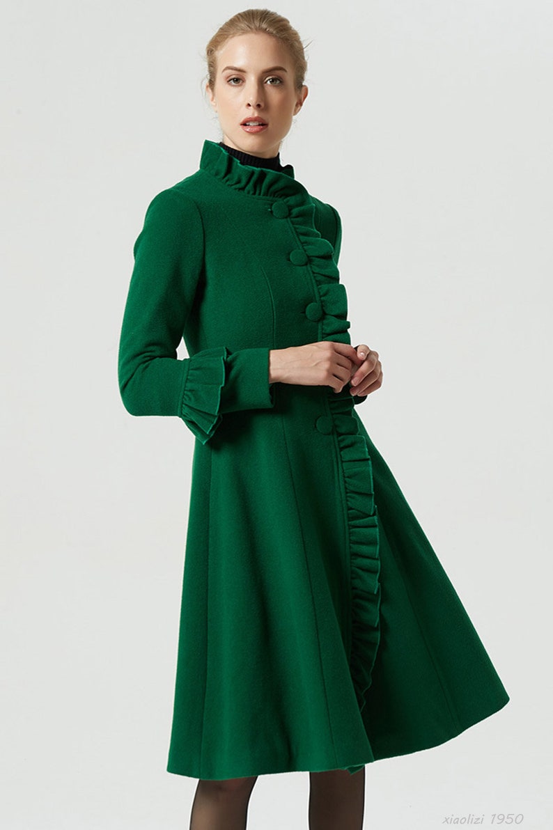May include: A green wool coat with a ruffled collar and cuffs. The coat has a fitted bodice and a flared skirt.