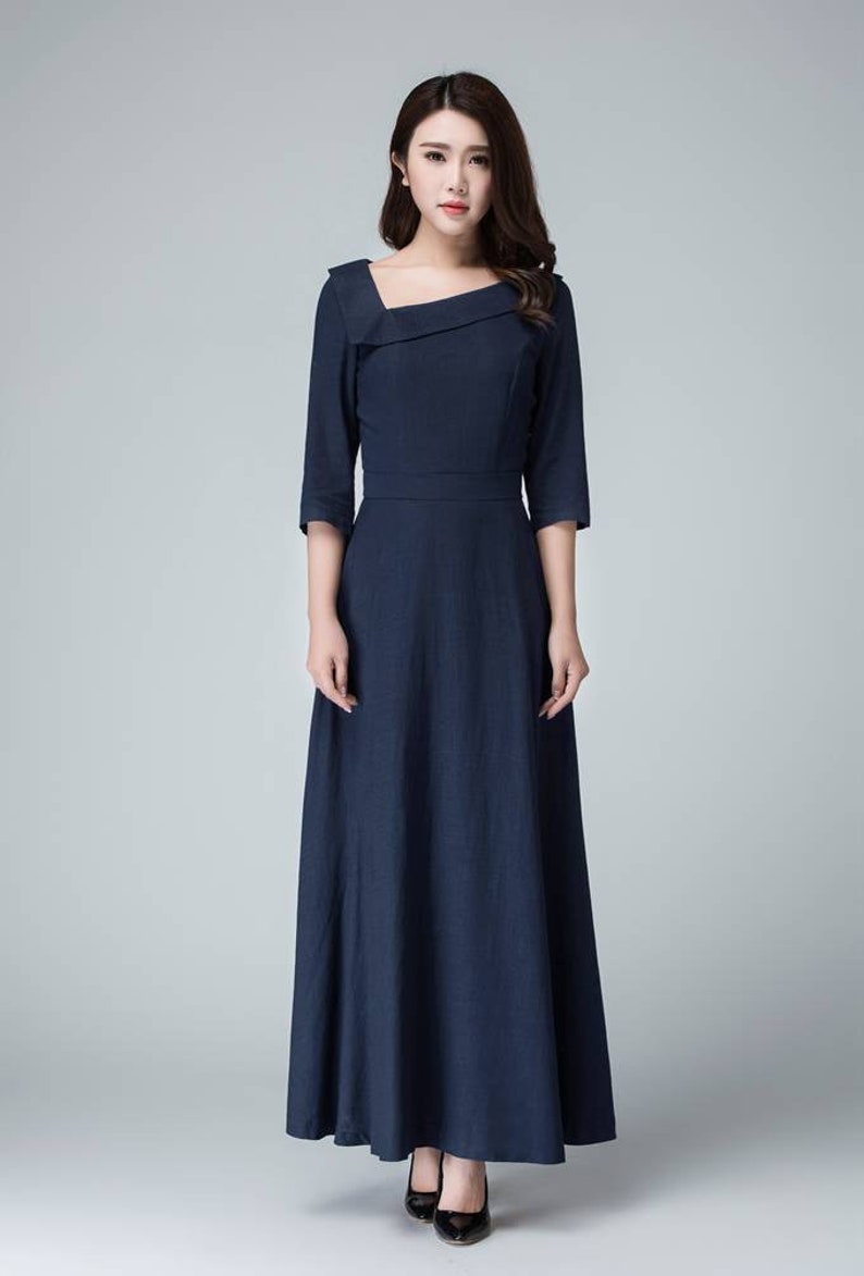 May include: A long, navy blue dress with a square neckline and a fitted bodice. The dress has a flowing skirt and three-quarter sleeves.