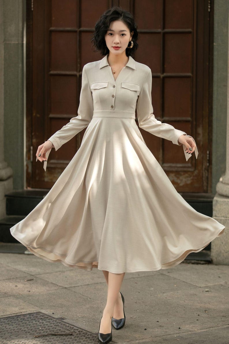 May include: A beige long-sleeved dress with a collared neckline, button closure, and a flared skirt.