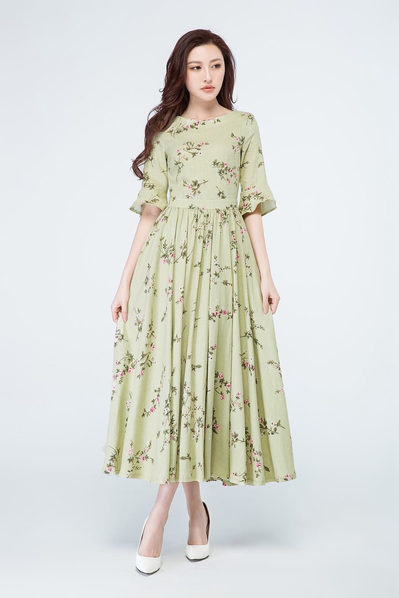Peut inclure: Robe vert clair &agrave; imprim&eacute; floral. Col rond, manches courtes et taille cintr&eacute;e. La jupe longue est orn&eacute;e de motifs floraux roses. La robe mesure environ 150 cm de long.