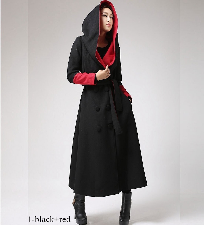 May include: A long black hooded coat with a red lining. The coat has a double breasted closure and a belt.