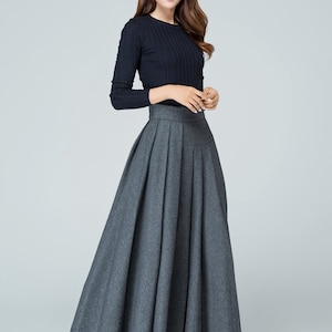 May include: A gray pleated maxi skirt with a high waistline. The skirt is made of a soft, flowing fabric and has a simple, elegant design.