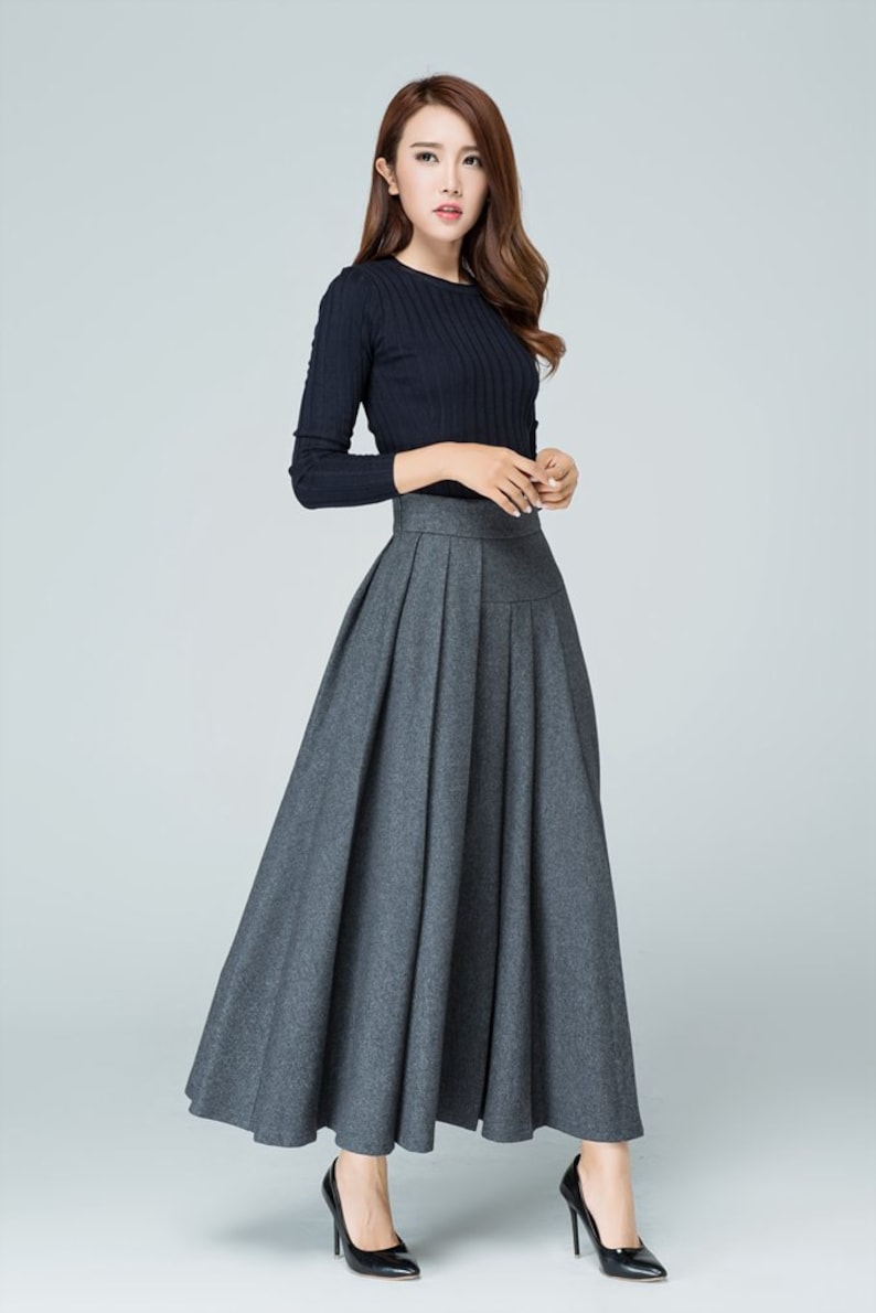 May include: A gray pleated maxi skirt with a high waistline. The skirt is made of a soft, flowing fabric and has a simple, elegant design.