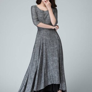 K&ouml;nnte beinhalten: Ein graues Maxikleid mit einem schwarzen Unterrock. Das Kleid hat einen runden Ausschnitt und 3/4 &Auml;rmel. Das Kleid ist aus einem leichten Stoff gefertigt und hat eine flie&szlig;ende Silhouette.