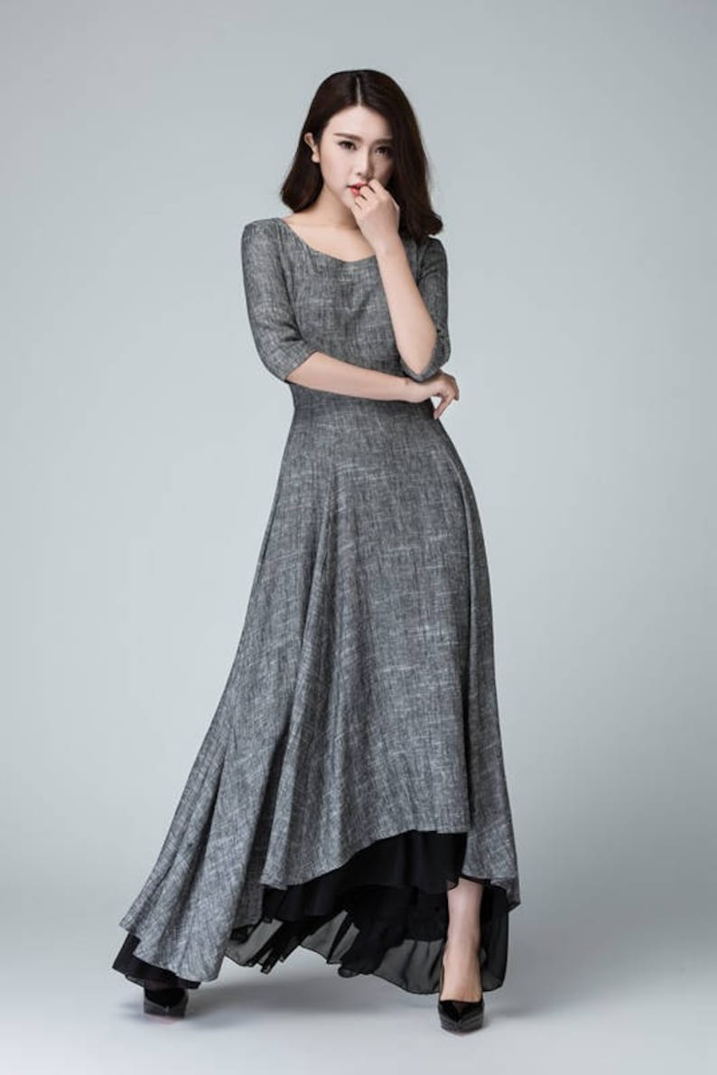 K&ouml;nnte beinhalten: Ein graues Maxikleid mit einem schwarzen Unterrock. Das Kleid hat einen runden Ausschnitt und 3/4 &Auml;rmel. Das Kleid ist aus einem leichten Stoff gefertigt und hat eine flie&szlig;ende Silhouette.