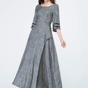 May include: A gray linen dress with a black trim on the sleeves. The dress has a fitted bodice and a flowing skirt.