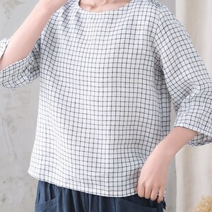 Op de afbeelding: Een wit en blauw geruit blouse met 3/4 mouwen. De blouse heeft een ronde hals en is gemaakt van een lichtgewicht stof.