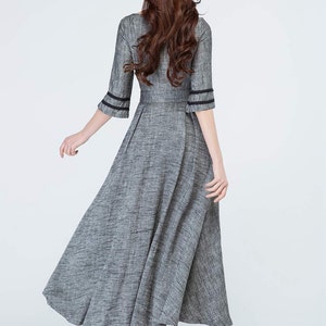 May include: A gray maxi dress with black trim on the sleeves. The dress has a fitted bodice and a flowing skirt.