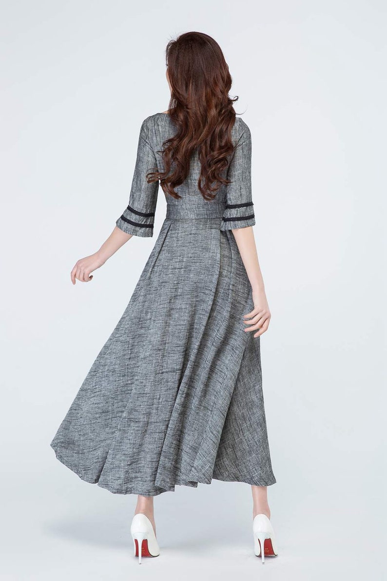 May include: A gray maxi dress with black trim on the sleeves. The dress has a fitted bodice and a flowing skirt.