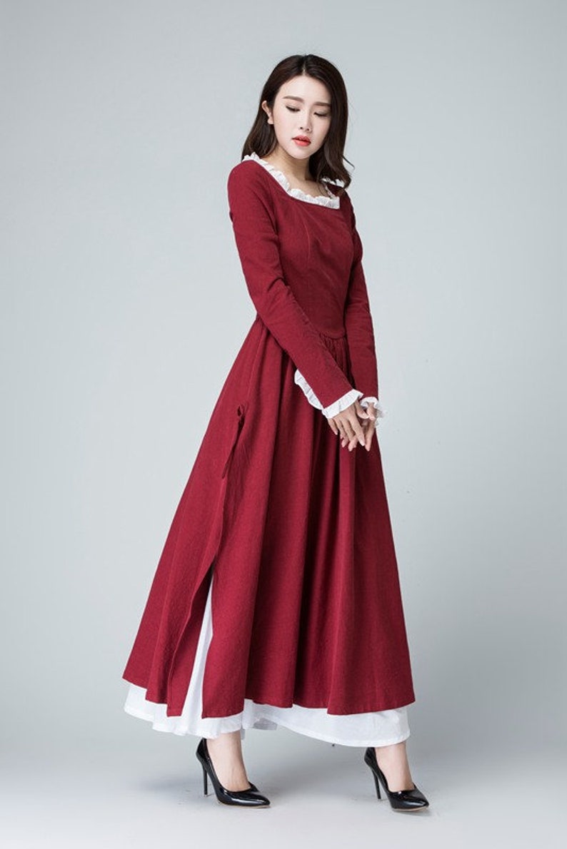 May include: A long, red dress with white lace trim at the neckline and cuffs. The dress has a square neckline and long sleeves. The skirt is full and flowing. The dress is made of a lightweight fabric and is perfect for a summer day.