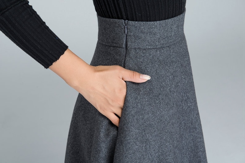 K&ouml;nnte beinhalten: Ein grauer Wollrock mit Rei&szlig;verschluss hinten. Der Rock hat eine hohe Taille und eine ausgestellte Silhouette.