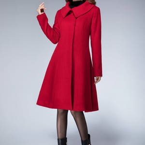 May include: A red wool coat with a wide collar and a flared skirt. The coat is knee-length and has a single button closure.