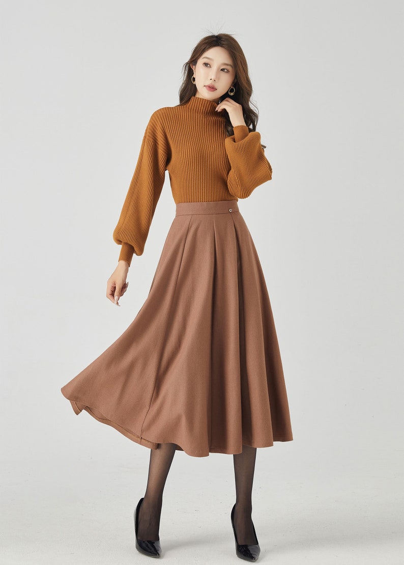 May include: A brown midi skirt with a high waist and a flared silhouette. The skirt is made of a soft, flowing fabric and has a simple, elegant design.