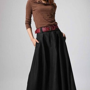 May include: A black maxi skirt with a wide red belt. The skirt has a pleated design and pockets on the sides.