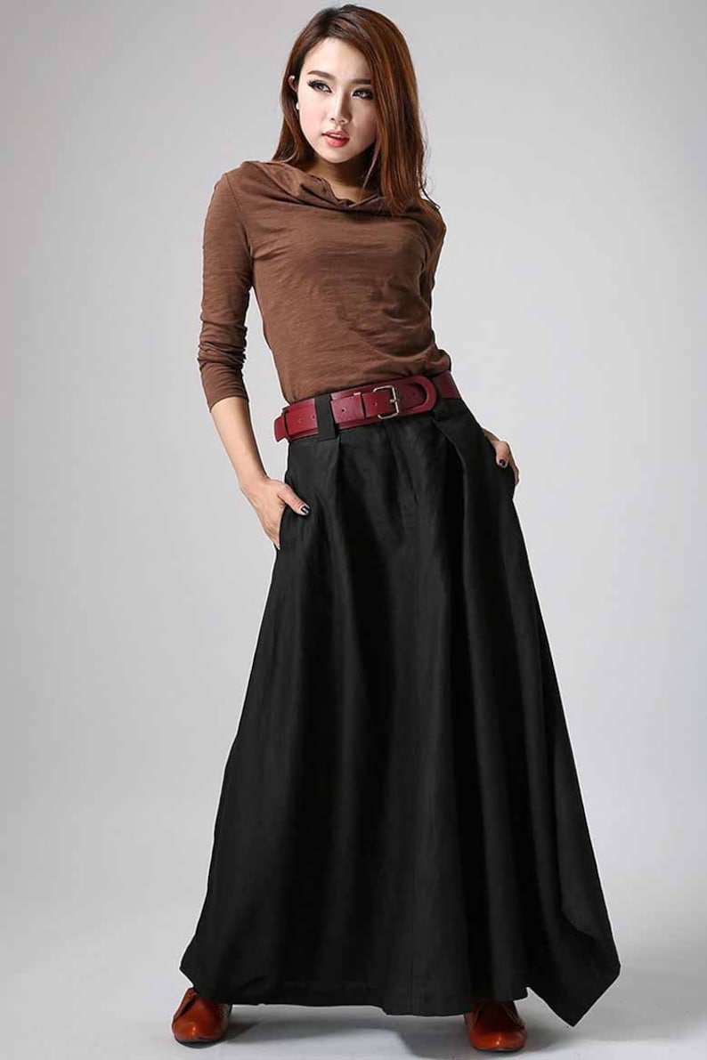 May include: A black maxi skirt with a wide red belt. The skirt has a pleated design and pockets on the sides.