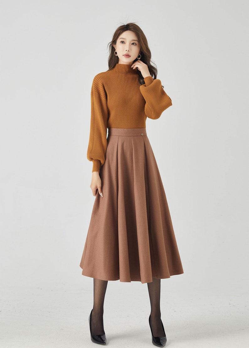 May include: A brown midi skirt with a high waist and a flared silhouette. The skirt is paired with a brown turtleneck sweater with long sleeves and a ribbed texture.