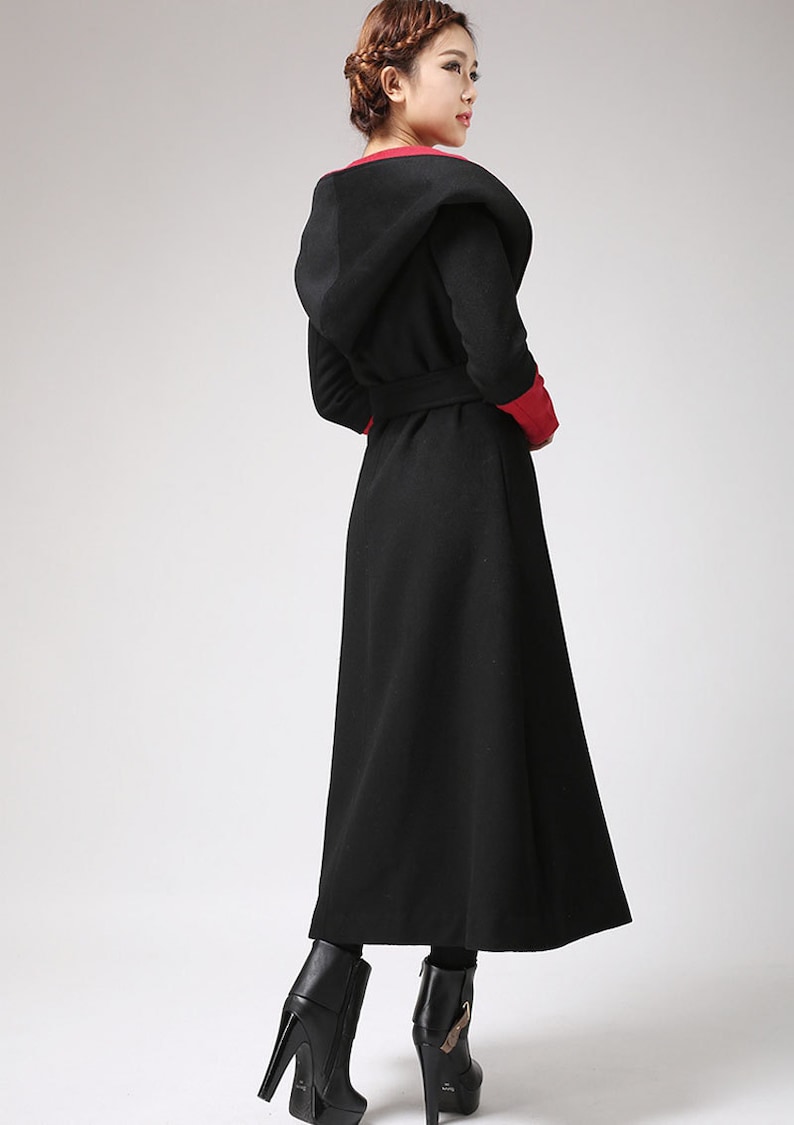May include: A long black hooded coat with a red trim around the hood and cuffs. The coat has a belt and a flowing skirt.
