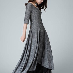 K&ouml;nnte beinhalten: Ein graues Maxikleid mit Rundhalsausschnitt und 3/4-&Auml;rmeln. Das Kleid hat einen flie&szlig;enden Rock und ist aus einem leichten Stoff gefertigt.