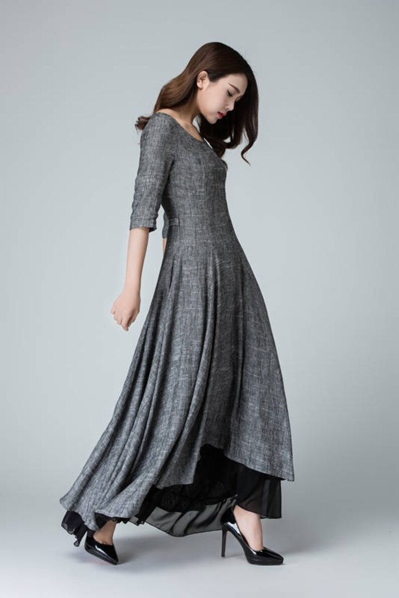 K&ouml;nnte beinhalten: Ein graues Maxikleid mit Rundhalsausschnitt und 3/4-&Auml;rmeln. Das Kleid hat einen flie&szlig;enden Rock und ist aus einem leichten Stoff gefertigt.