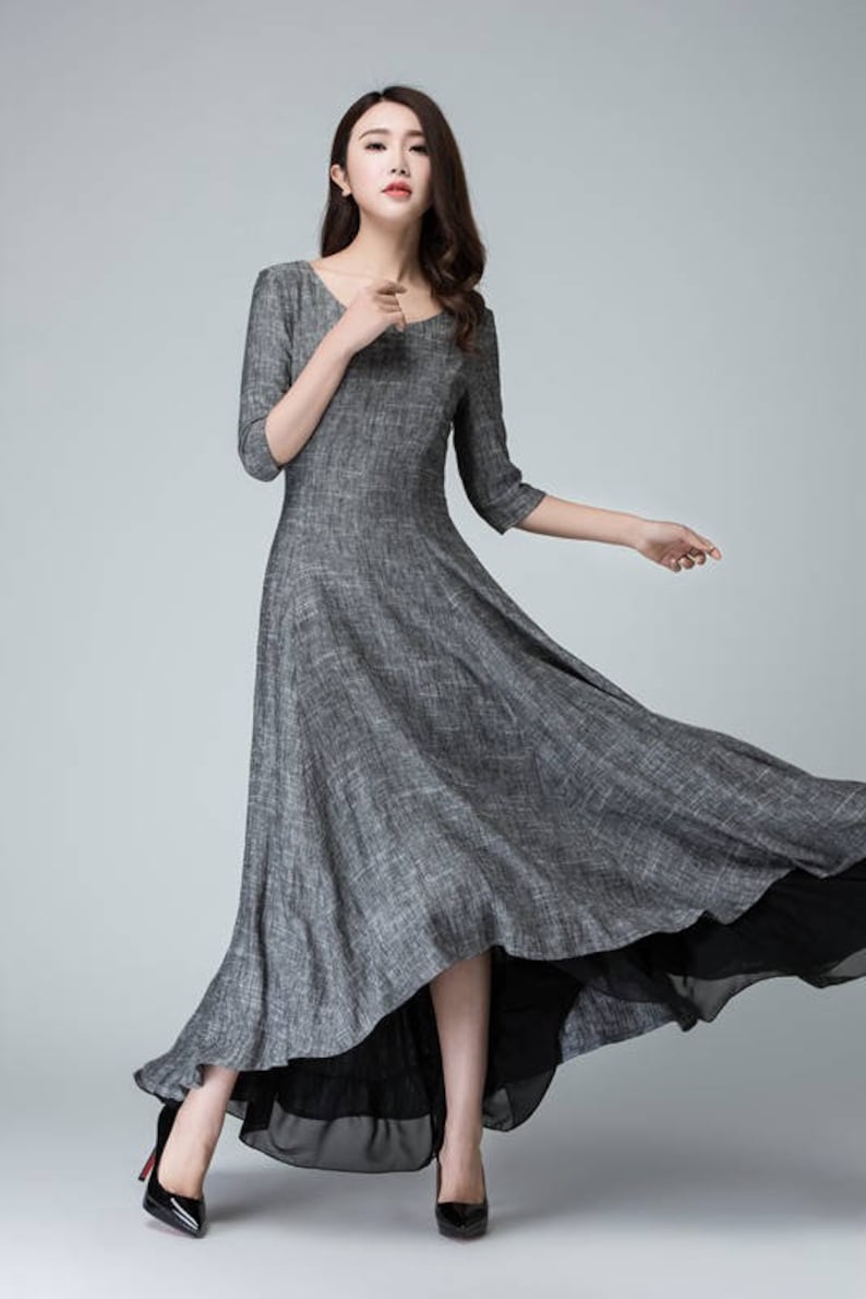 K&ouml;nnte beinhalten: Ein graues Leinen-Maxikleid mit einem hohen, niedrigen Saum. Das Kleid hat einen runden Ausschnitt und 3/4 &Auml;rmel.
