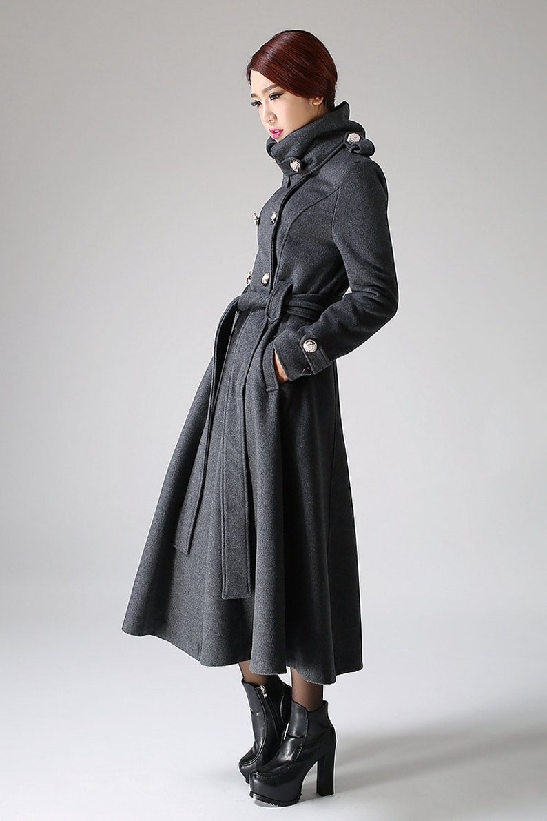 May include: A long, gray, double-breasted coat with a high collar and a belt. The coat has silver buttons and a flared skirt.