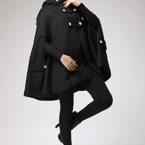 May include: A black hooded cape with a double-breasted button closure and pockets. The cape is made of a soft, warm fabric and has a relaxed fit.