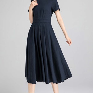 May include: A navy blue midi dress with a boat neck and short sleeves. The dress has a fitted bodice and a flowing skirt.