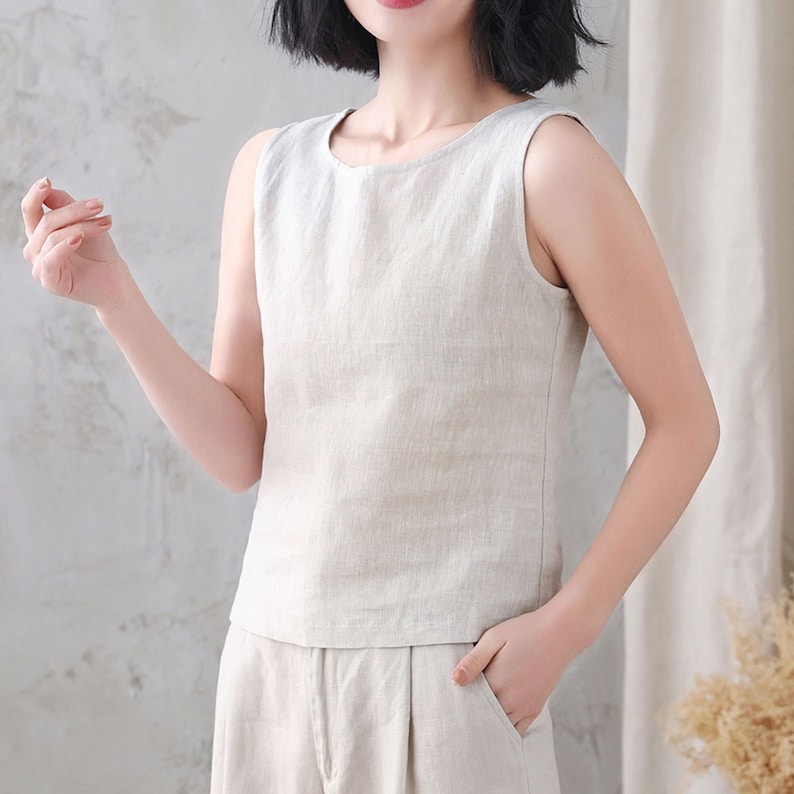 Pu&ograve; includere: Un top in lino senza maniche di colore beige chiaro. Il top ha una scollatura rotonda e una vestibilit&agrave; rilassata.