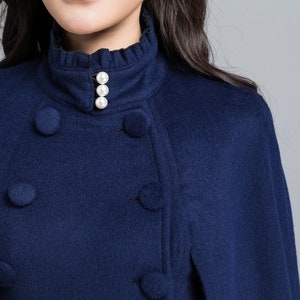 Puede incluir: Un abrigo azul marino de doble botonadura con cuello alto y botones de perla.