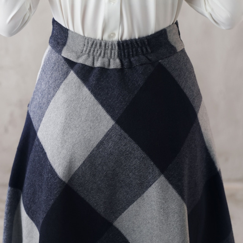 May include: A gray and navy blue plaid skirt with an elastic waistband.
