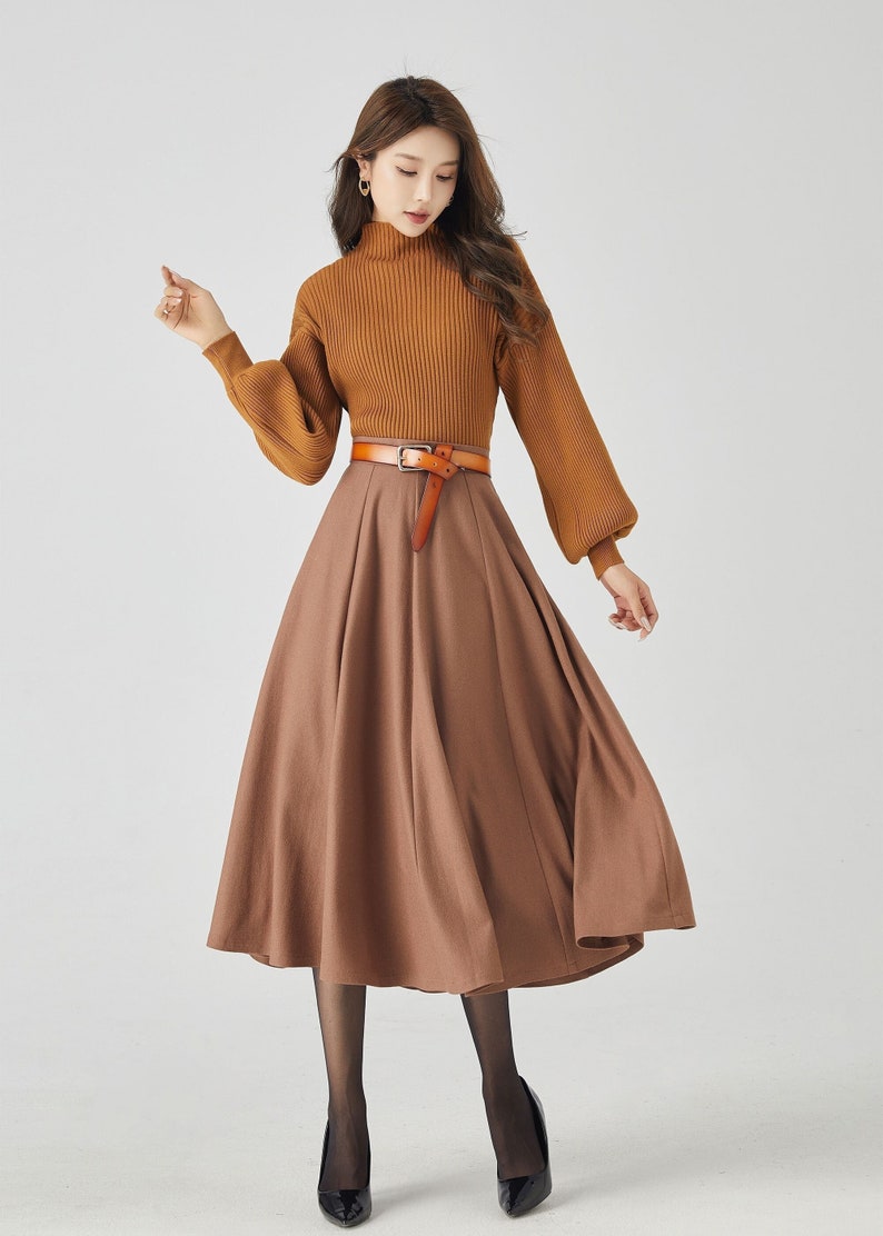 May include: A woman wearing a brown turtleneck sweater with a brown skirt and a brown leather belt. She is wearing black tights and black heels.