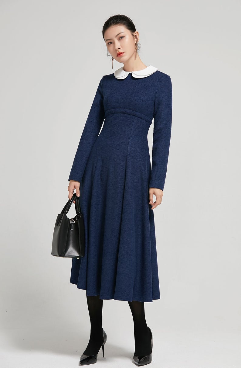 Puede incluir: Un vestido midi azul marino con cuello blanco de Peter Pan y mangas largas. El vestido tiene un corpi&ntilde;o ajustado y una falda acampanada.