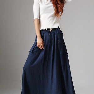 May include: A navy blue maxi skirt with a zipper closure and two large pockets on the front. The skirt has a pleated design and is made of a lightweight fabric.