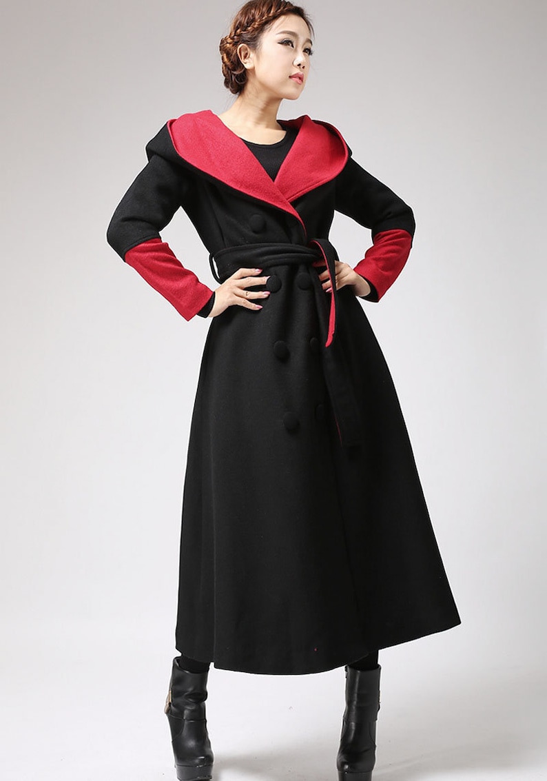May include: A long black coat with a red lining and a hood. The coat has a double-breasted closure and a belt.