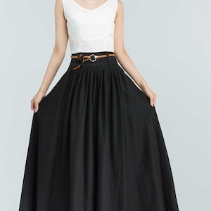 May include: A black maxi skirt with a brown belt and a gold buckle. The skirt has pleats and is made of a lightweight fabric.