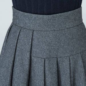 May include: A gray pleated skirt with a high waist.
