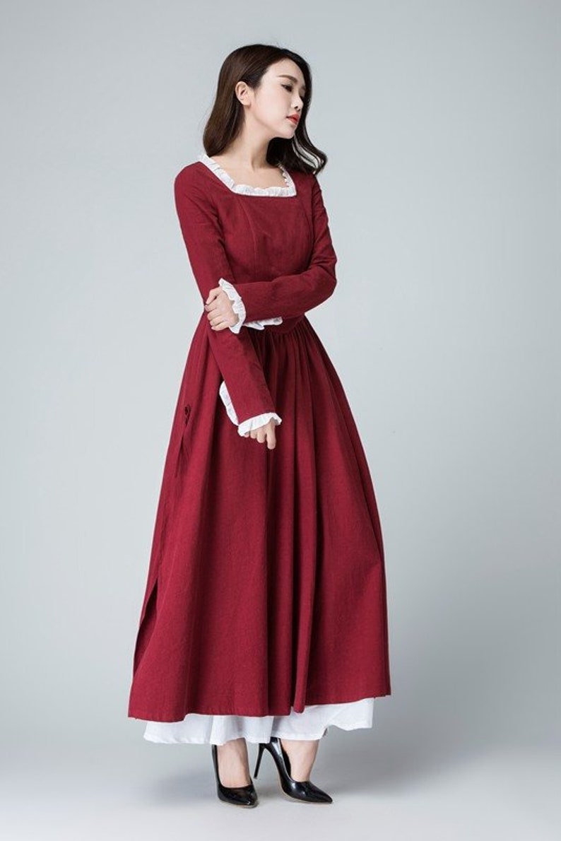 May include: A long-sleeved, burgundy dress with a white lace trim around the neckline and cuffs. The dress has a fitted bodice and a full skirt.