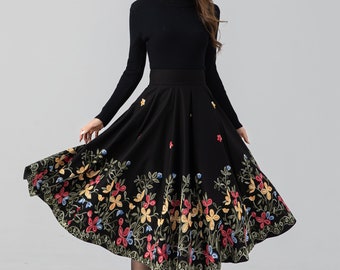 May include: A black midi skirt with a floral embroidery design. The skirt is knee-length and has a full, flowing silhouette.