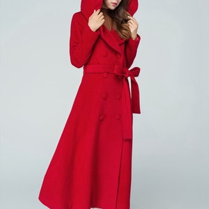 May include: A long red hooded coat with a double breasted closure and a belt. The coat has a flared skirt and is made of a soft, warm fabric.
