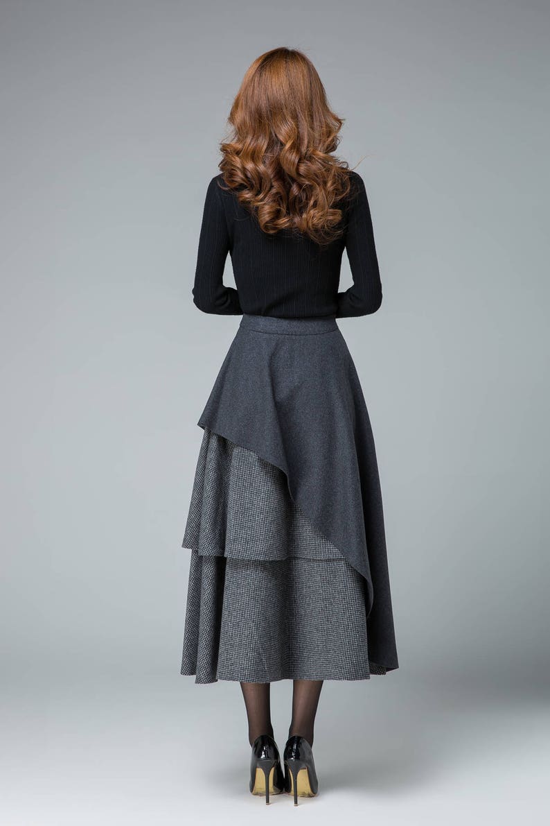 May include: A black long-sleeved shirt with a layered gray and black skirt. The skirt has a unique asymmetrical design with a longer layer in the back.