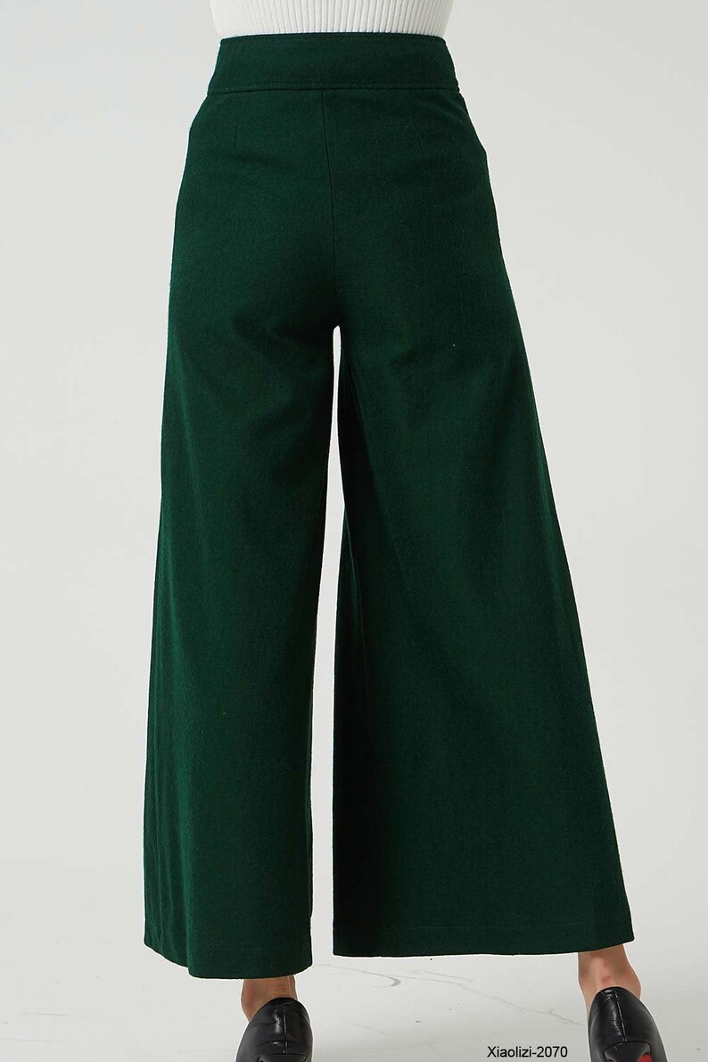 May include: A pair of wide-leg trousers in a dark green colour. The trousers have a high waist and a relaxed fit.