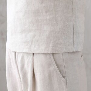 Pu&ograve; includere: Un paio di pantaloni di lino beige con una tasca anteriore. I pantaloni sono realizzati in un tessuto leggero e traspirante.
