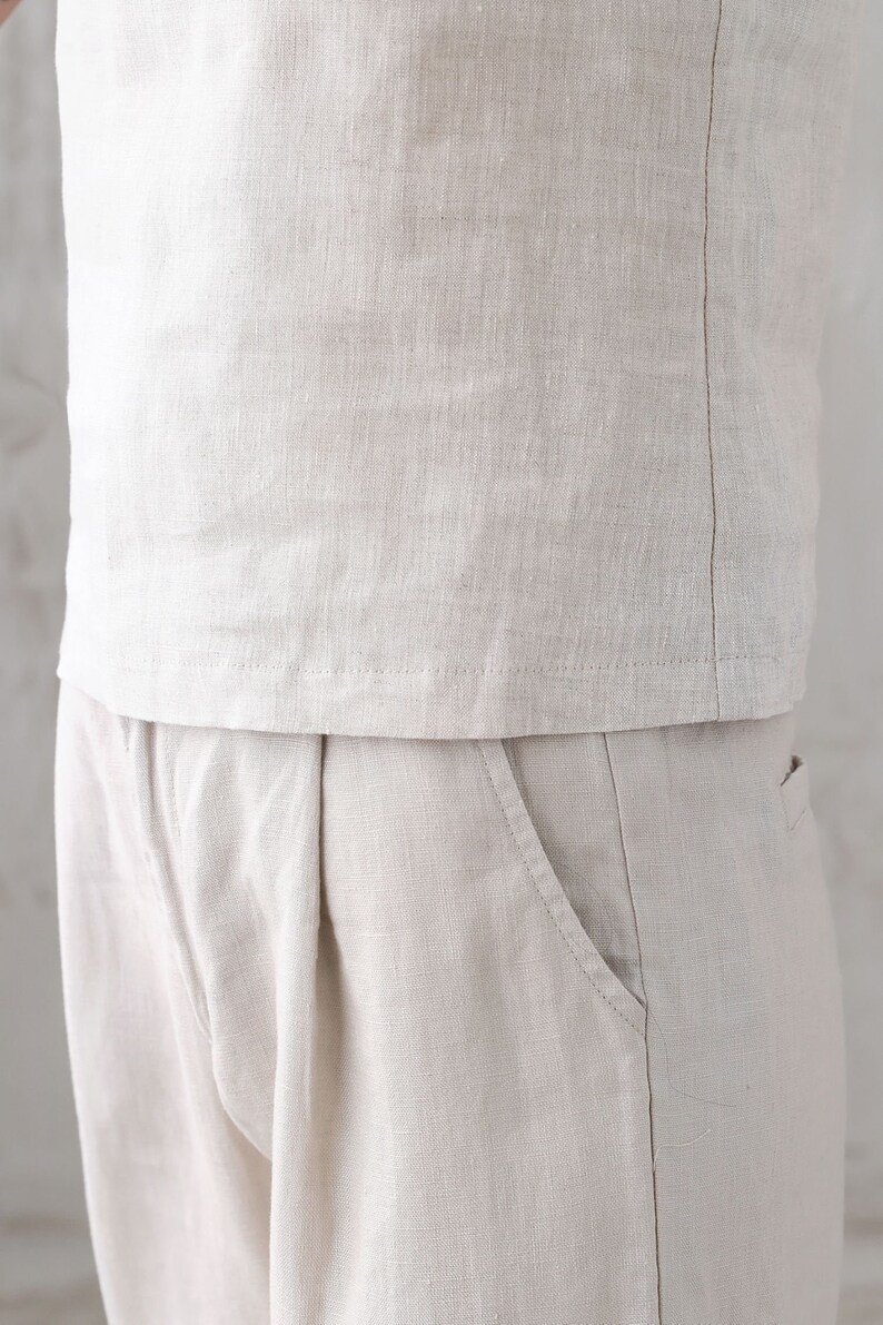 Pu&ograve; includere: Un paio di pantaloni di lino beige con una tasca anteriore. I pantaloni sono realizzati in un tessuto leggero e traspirante.