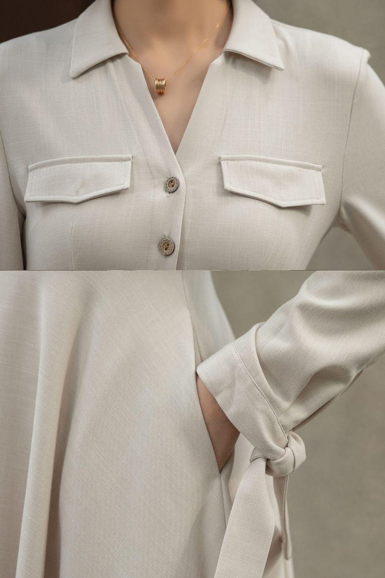 May include: A beige linen dress with a collared neckline, long sleeves, and a button-up front. The dress has two flap pockets on the chest and a tie detail at the cuffs.
