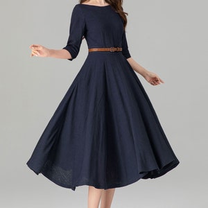 May include: A navy blue midi dress with a brown belt. The dress has a round neckline and 3/4 sleeves. The dress is made of a soft, comfortable fabric.