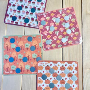 May include: Four square cards with colorful patterns and metallic circles. The cards feature designs of cupcakes, mushrooms, trees, and pumpkins. Each card has the text "Save" followed by a number, such as "Save 40" or "Save 50".