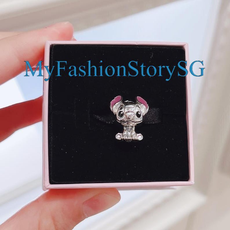 Pu&ograve; includere: Un ciondolo d'argento con Stitch di Lilo & Stitch. Stitch &egrave; raffigurato seduto, con i suoi grandi occhi caratteristici e le orecchie rosa. Il ciondolo &egrave; in una scatola rosa con il testo "MyFashionStorySG".