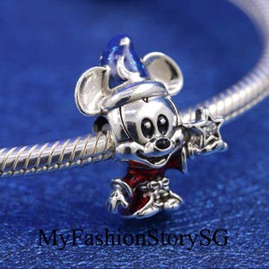 May include: Silver charm featuring Mickey Mouse dressed as a wizard. He is wearing a blue and silver hat with a star on top, a red and silver robe, and holding a silver wand with a star on the end.