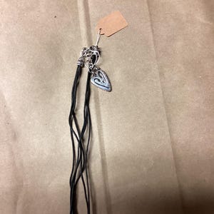 May include: A black leather cord necklace with two silver heart charms. The necklace is on a brown paper background.