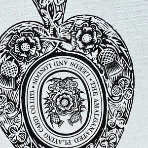 May include: Black and white playing card illustration featuring a heart shape with floral and thistle designs. The text reads "THE AMALGAMATED PLAYING CARD CO. LTD. LONDON AND LEEDS". The spade symbol is at the top.